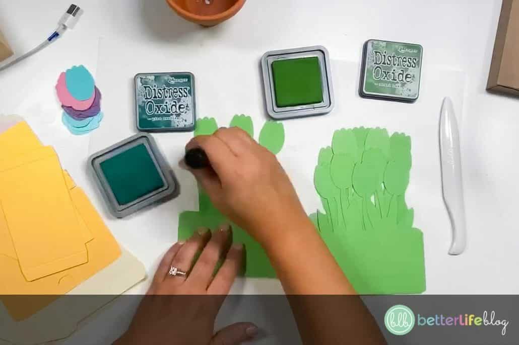 Adding glue to green pieces of cardstock