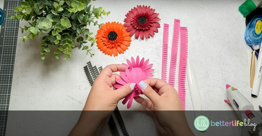Folding pink paper petals inwards to create a realistic look