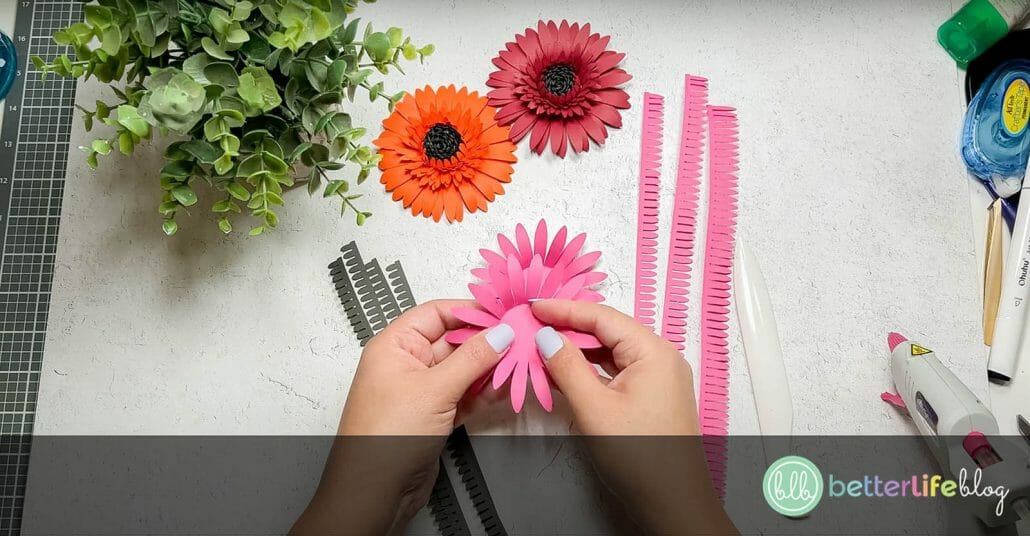Folding pink paper petals outwards to create a realistic look