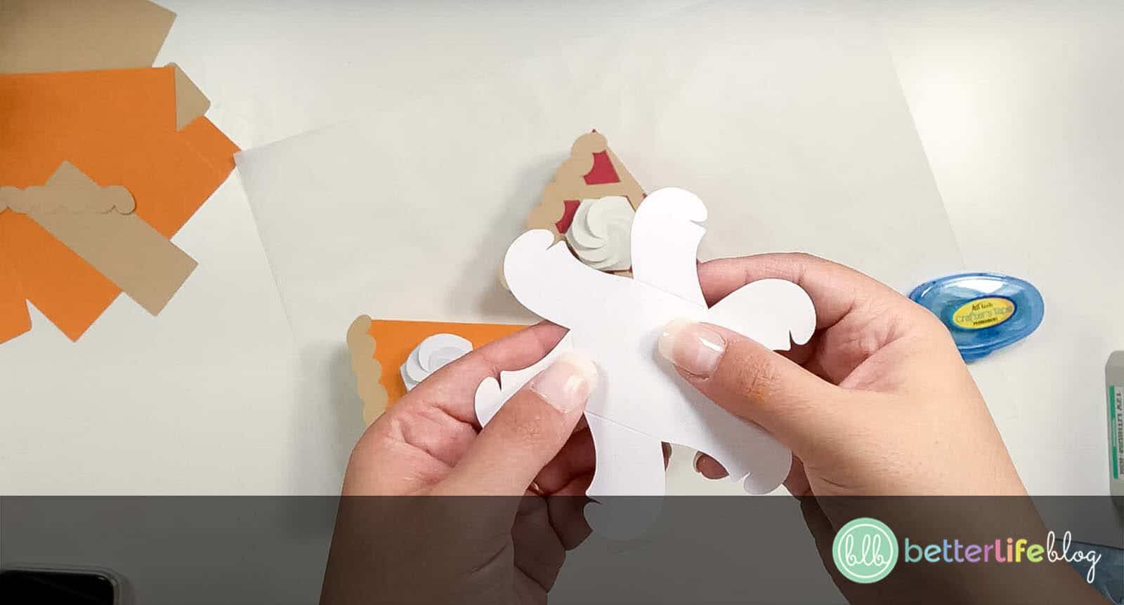 Folding a white piece of cardstock, freshly cut by a Cricut machine