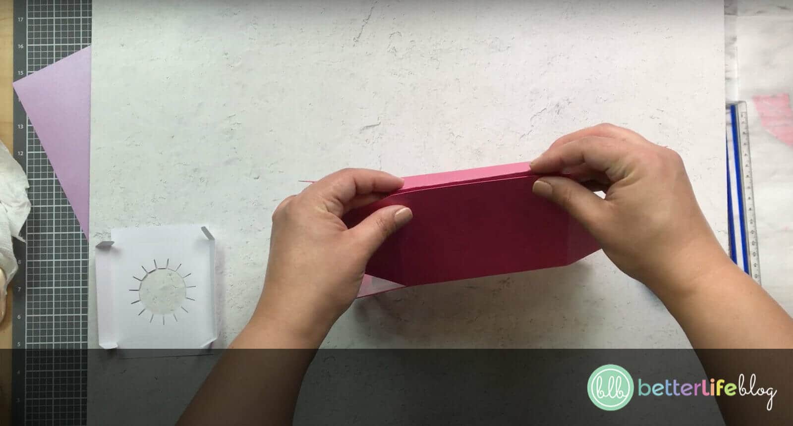 Folding a large piece of pink cardstock to make a Cricut Cupcake Holder Box