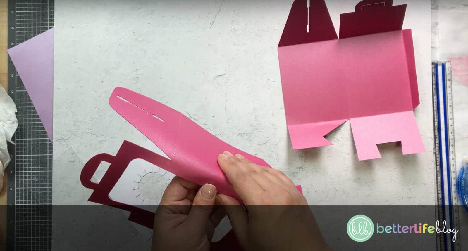 Folding a large piece of pink cardstock cut out by a Cricut machine