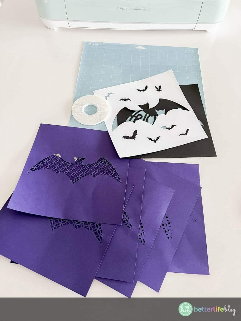Designs cut out on purple, white, and black cardstock to make a Halloween Shadow Box.