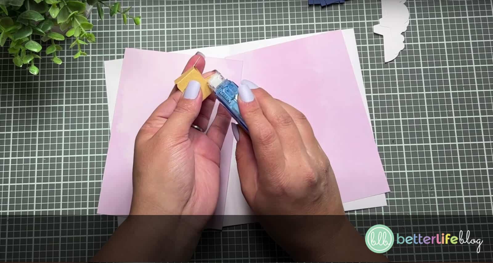 Adding crafter’s tape onto the tabs of a yellow piece of cardstock