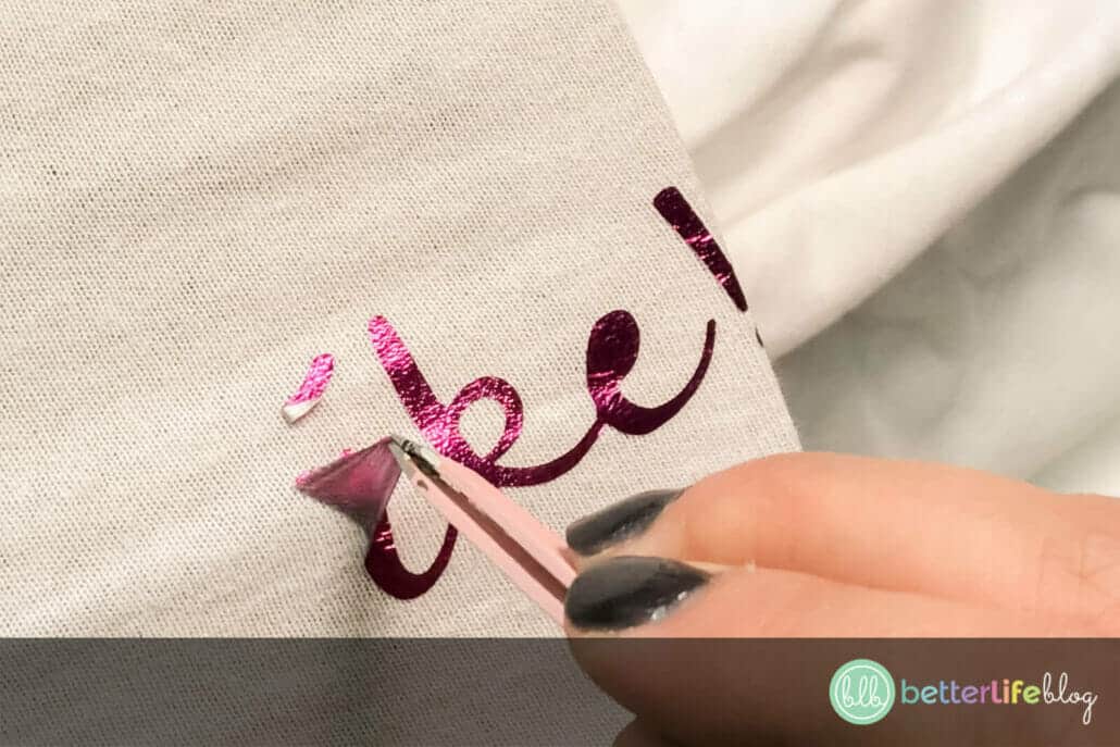 Using tweezers to remove HTV from a white tshirt